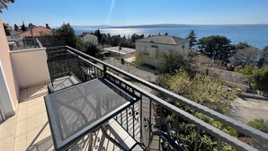 A balcony with a metal railing overlooking a residential area with houses and a body of water in the distance. - Soba Kira 6 (Dramalj)