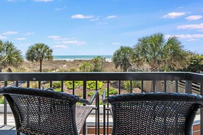 A balcony with wicker chairs, a view of the beach, and palm trees. - New Direct Oceanfront 3BR,2B - Private WaterPoint! (North Myrtle Beach)