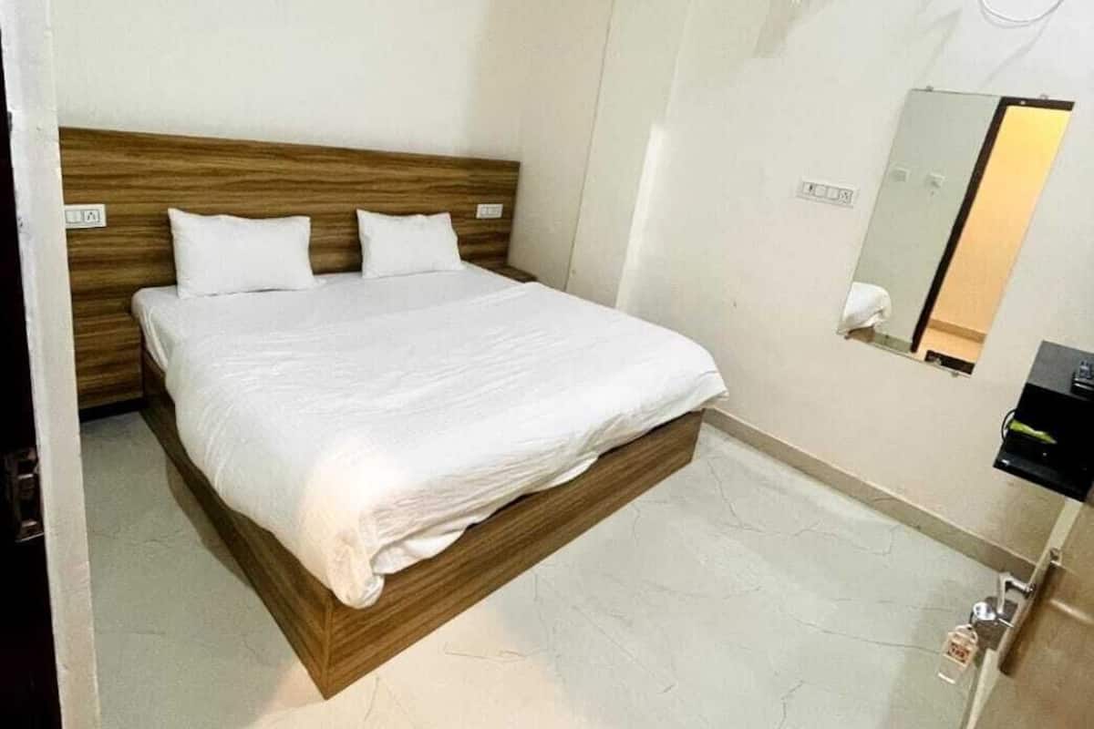 Ein Schlafzimmer mit einem hölzernen Kopfteil, einem Bett mit weißer Bettwäsche, einem Deckenventilator, einer Klimaanlage, einem Spiegel und einer Tür mit Griff.
