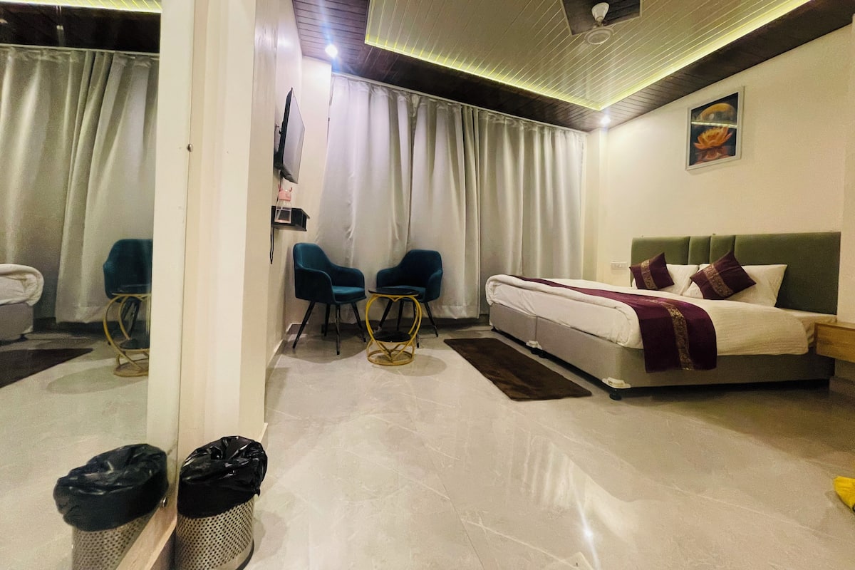 Ein Hotelzimmer mit einem Bett, zwei Stühlen, einem Fernseher und einer Deckenleuchte.