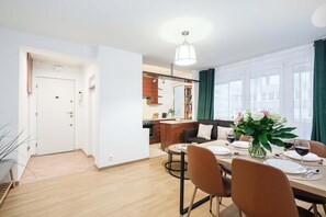 A modern apartment with a dining area, kitchen, and a living space with a sofa and a coffee table. - Lumina opposite the Palace of Culture and Science (Warszawa BIG)