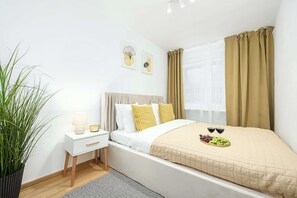 A neatly arranged bedroom with a bed, bedside table, lamp, and a potted plant.