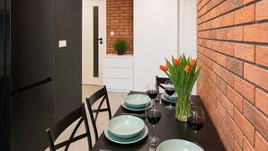 Une cuisine moderne avec un réfrigérateur noir, une table à manger dressée avec des assiettes, des verres et un vase de fleurs.
