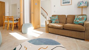 Una sala de estar con un sofá, una mesa de comedor con sillas y una escalera.