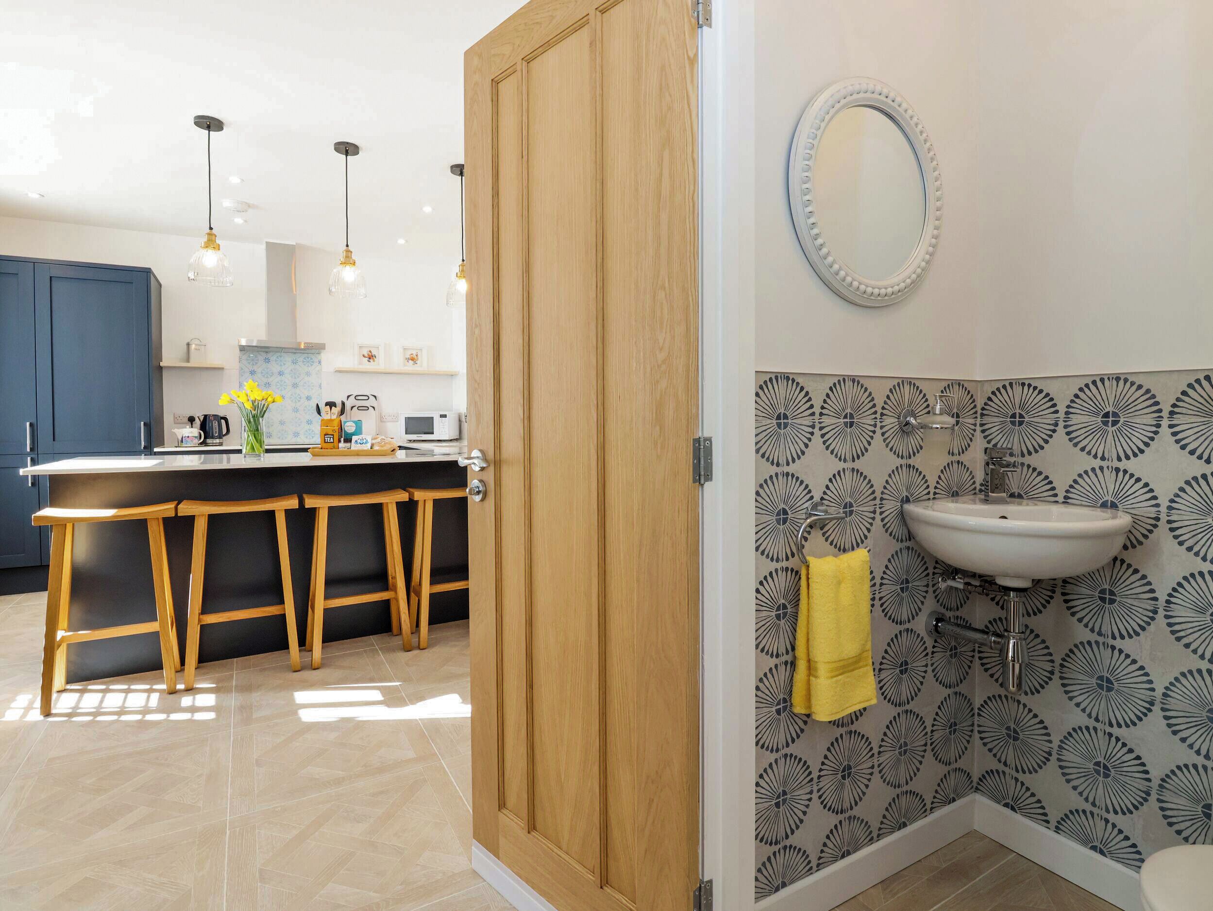 A modern kitchen with wooden stools, a white countertop, and pendant lighting.