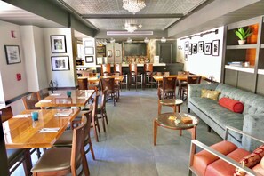 A restaurant with multiple dining tables and chairs, a bar area, and a seating area with a sofa and chairs. - Grove Cove  Pool, Parking, Central Coconut Grove (Miami)