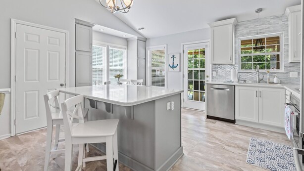 A modern kitchen with white cabinetry, a central island, and a stainless steel refrigerator.