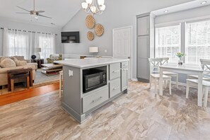 Relax in a spacious living area with a sofa, dining table, and kitchen with microwave.