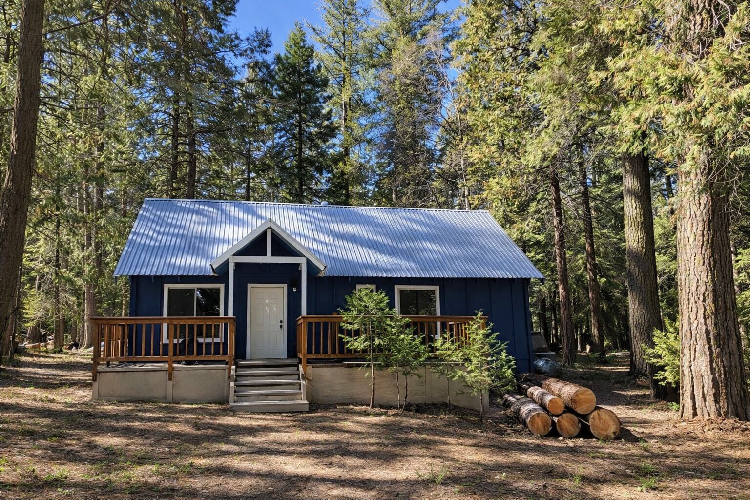A small cabin with a metal roof, wooden deck, and a front door.