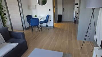 A modern living room with a sofa, a coffee table, and a dining area with chairs and a table.