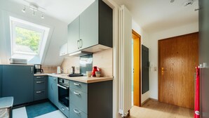 Une cuisine moderne avec des meubles gris, un four encastré et une fenêtre qui laisse entrer la lumière naturelle.