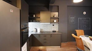 A modern kitchen with dark cabinetry, a black countertop, and a chalkboard menu on the wall. - Chersonissos Central Apartment (Hersonissos)