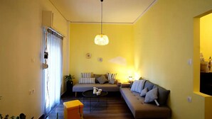 A living room with a sofa, a coffee table, and a hanging light fixture. - Chersonissos Central Apartment (Hersonissos)