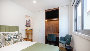 A hotel room with a bed, a desk, two chairs, and a TV. - Matosinhos Seaside Cozy Studio (Matosinhos)