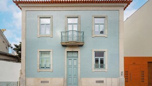 A building with a tiled facade, a central entrance door, and a balcony with a metal railing. - Matosinhos Seaside Cozy Studio (Matosinhos)