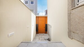 A narrow hallway with a wooden door at the end, a small step, and a light switch on the wall. - Matosinhos Seaside Cozy Studio (Matosinhos)