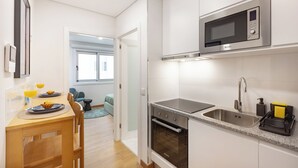 A modern kitchen with a built-in microwave, oven, and stainless steel sink. - Matosinhos Seaside Cozy Studio (Matosinhos)