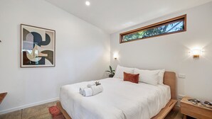 A modern bedroom with a large bed, a framed abstract painting, a window with a view, and a bedside table with a lamp. - Secluded Bellbrae sanctuary (Bellbrae)