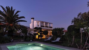 A pool area with lounge chairs, a well-maintained garden, and a building with a distinctive architectural style. - Villa Hope -Luxury 3-bedroom villa with AC, WiFi in lovely Buenas Noches (Buenas Noches)