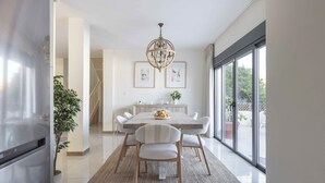 A modern dining area with a wooden table, white chairs, and a chandelier. - Villa Hope -Luxury 3-bedroom villa with AC, WiFi in lovely Buenas Noches (Buenas Noches)
