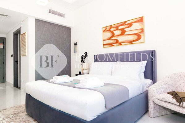 A modern bedroom with a large bed, a headboard, and a wall-mounted abstract painting.