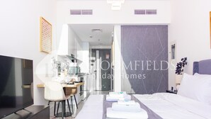 Une chambre d’hôtel avec un lit, un bureau, une chaise, une télévision et une salle de bain visible à travers une porte ouverte.