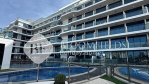 Un hôtel moderne à plusieurs étages, doté d’une piscine et caractérisé par une façade en verre incurvée et de nombreux balcons.