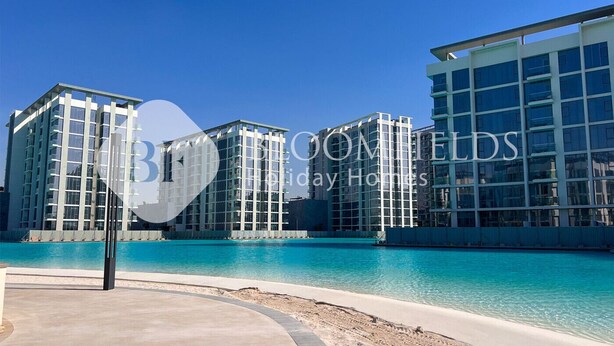 A modern hotel with a pool area and clear blue waters. - Bloomfields STU Riviera Skies In Meydan (Dubai)