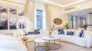 Ein modernes Wohnzimmer mit einem weißen Sofa, goldenen Akzenten und abstrakter Kunst an der Wand.