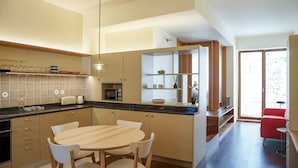 A modern kitchen with a central island, white chairs, and a dining table.