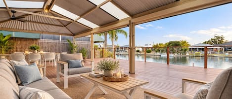 A covered outdoor seating area with a view of a pool and marina.