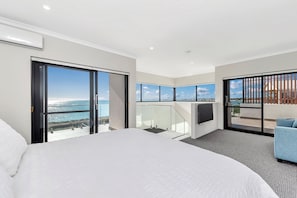 A modern hotel room with a large bed, a balcony with a view of the sea, and a TV mounted on the wall. - Coastal Bliss with Marina Views-Neaby Cafes (Mandurah)