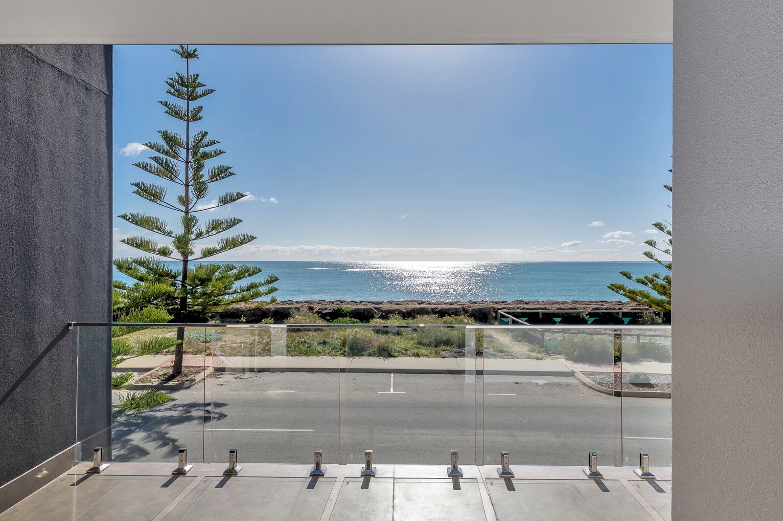 A balcony with a view of the ocean and a rocky shoreline.