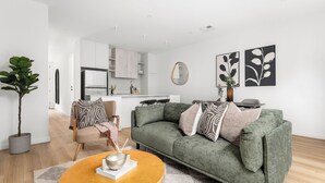 A modern living room with a green sofa, a wooden coffee table, and a potted plant. - Foundry Lane Apartments by Urban Rest (Bowden)
