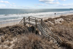 Eine Holztreppe führt hinunter zu einem Strand mit Blick auf das Meer.