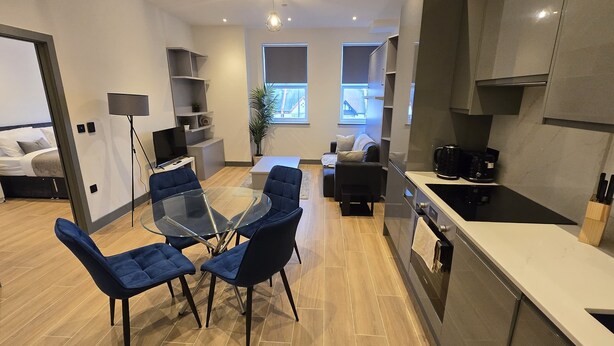 A modern kitchen with a dining area, a sofa, and a TV. - Finchley Perfect 1-Bed - Work & Leisure (London)