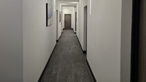 A modern hallway with a dark tiled floor, white walls, and recessed lighting. - Finchley Perfect 1-Bed - Work & Leisure (London)