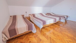 Une pièce avec trois lits en bois alignés contre un mur blanc, chacun étant recouvert d’une couverture à rayures.