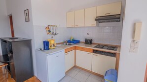 Une cuisine de taille réduite, équipée d’un réfrigérateur, d’une cuisinière, d’un évier et de placards.