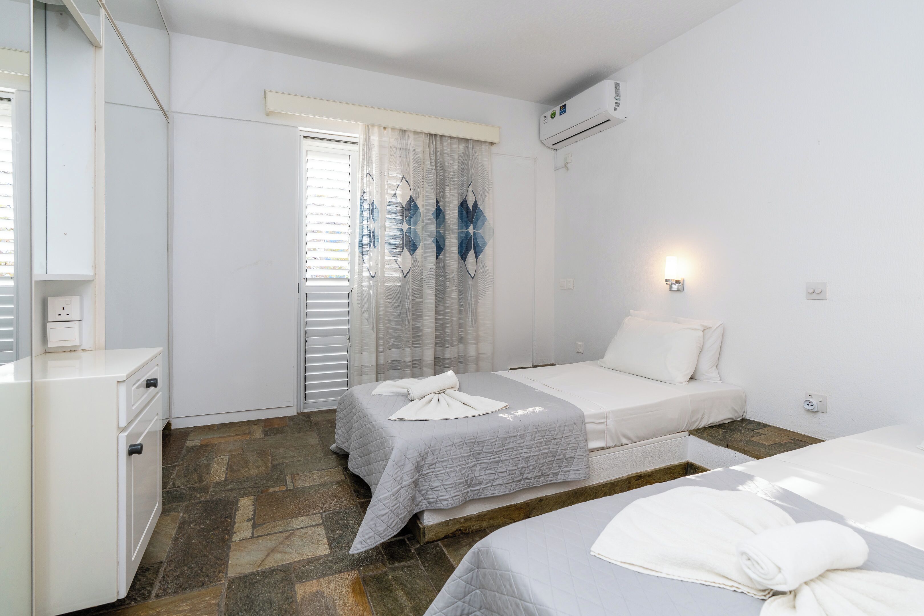 Ein Hotelzimmer mit zwei Betten, einer kleinen Küchenzeile und einem Badezimmer.