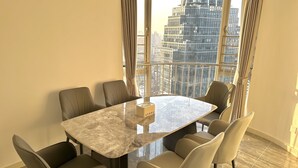Une salle de réunion moderne, dotée d’une table en marbre et de fauteuils en cuir, de grandes fenêtres avec des rideaux et offrant une vue sur la ville.