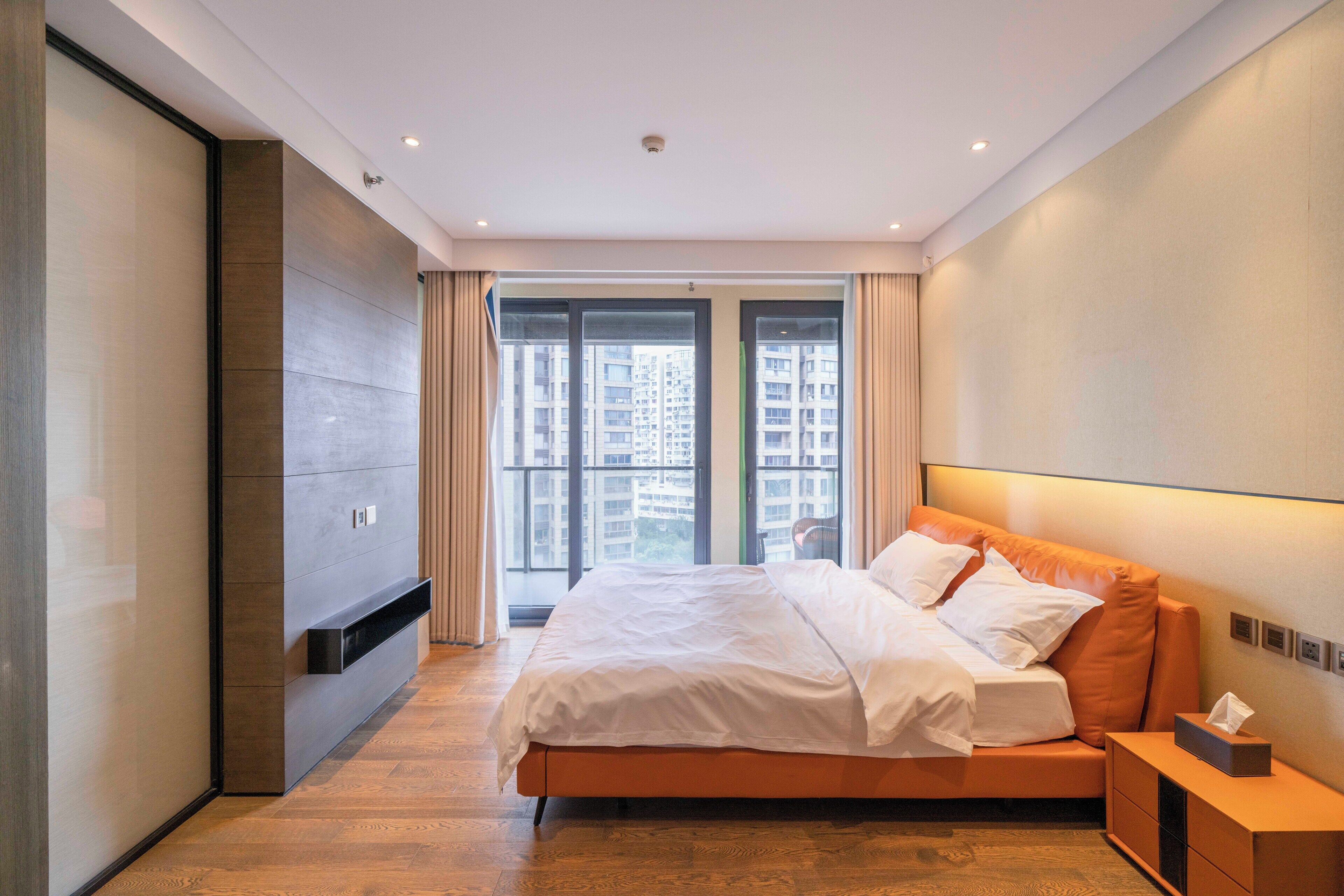 Une chambre d’hôtel moderne dotée d’un grand lit, d’un téléviseur à écran plat et offrant une vue sur les gratte-ciel.