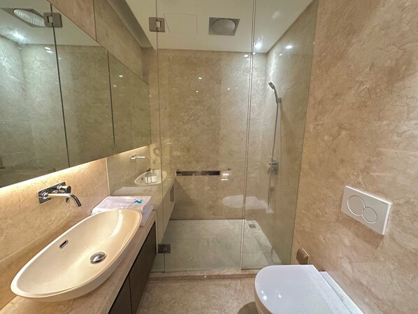 Une salle de bain moderne avec un lavabo beige, une douche à l’italienne et des toilettes blanches.