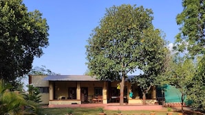 A two-story building with a covered porch and a dirt driveway. - Alate's guest house (Bhor)