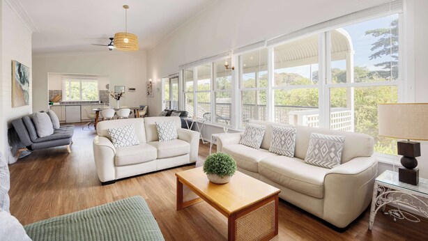 A spacious living room with a large window, a ceiling fan, and a dining area.