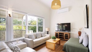 A living room with a sofa, a coffee table, a TV, and a large window.