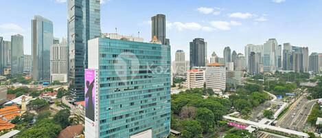 Un edificio de gran altura con fachada de vidrio moderna, rodeado de otros edificios altos y una calle transitada con vehículos.