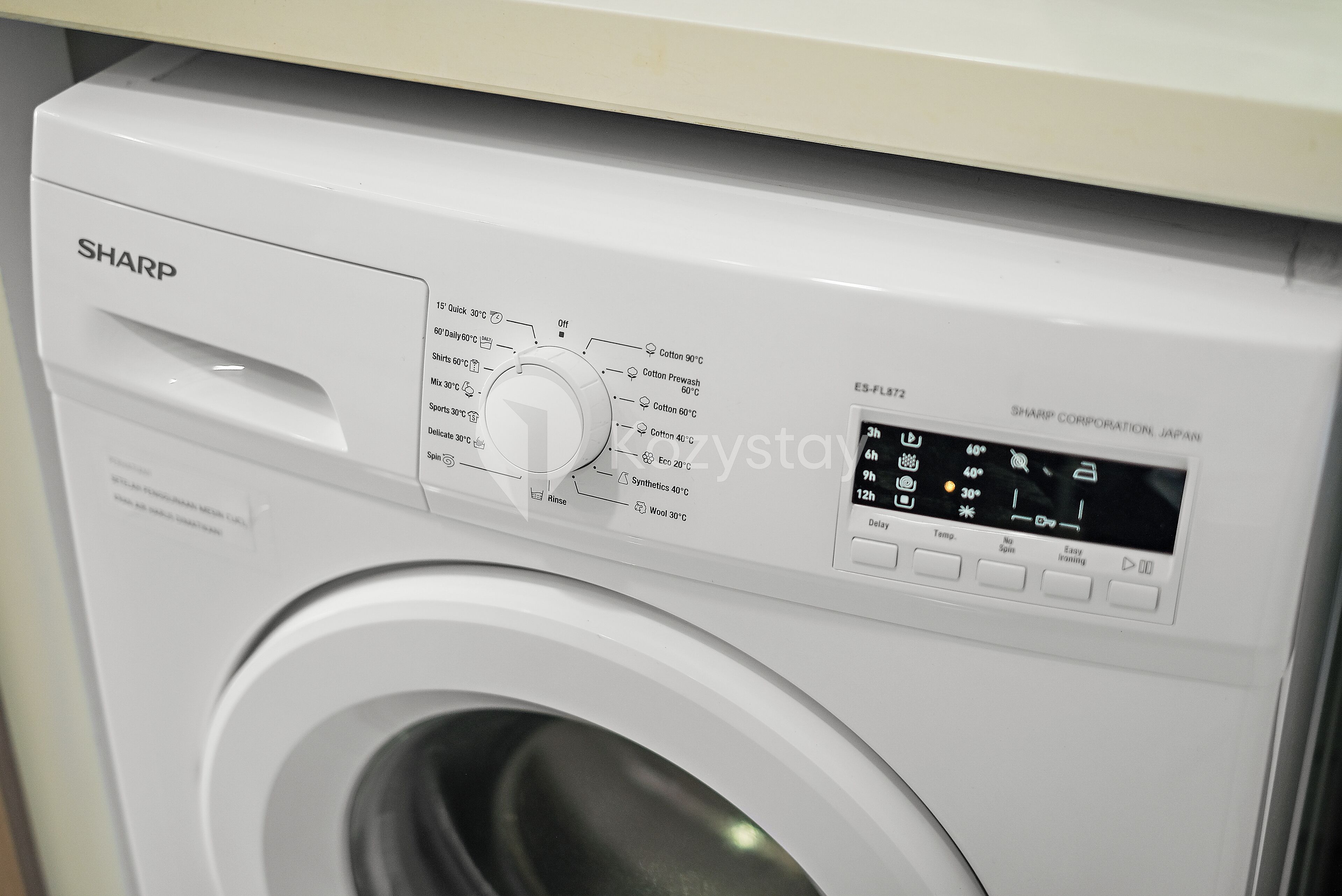 A white Sharp washing machine with a control panel and a digital display.
