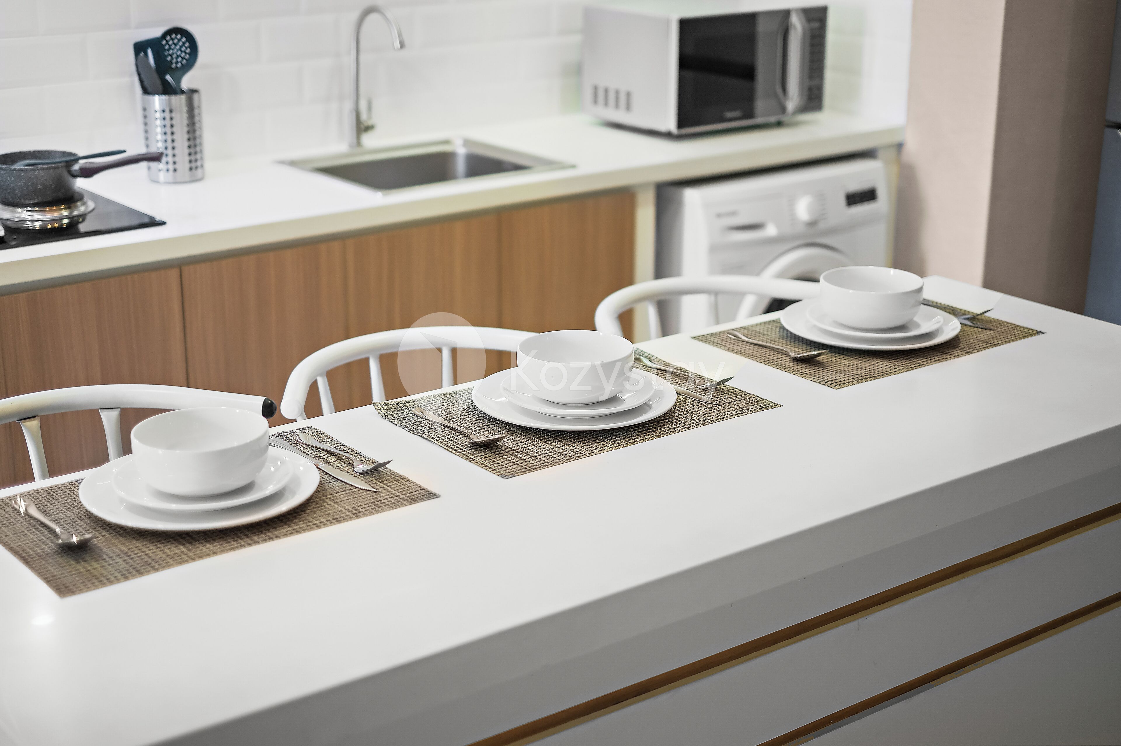 A modern kitchen with white countertops, a microwave, and a sink.