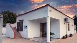 A white building with a tiled roof, a staircase, and a covered entrance. - Panoramic Villa with Infinity Pool – Relax and Comfort in Sicily (Sicilia)